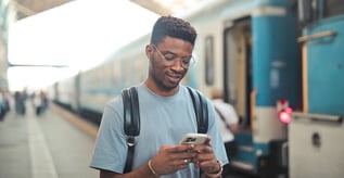 Man looking at phone next to train