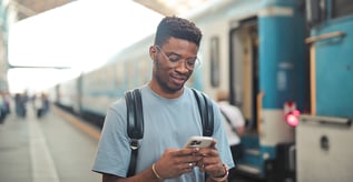 Man looking at phone next to train