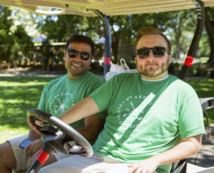 Two Fluent Inc. employees smiling and sitting in a golf cart at the annual charity golf outing